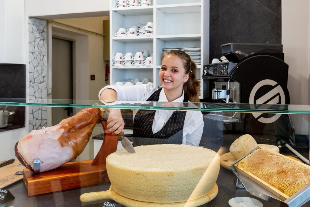 une femme coupe un morceau de pain sous une table de verre dans l'établissement Hotel Vela d'Oro, à Rimini