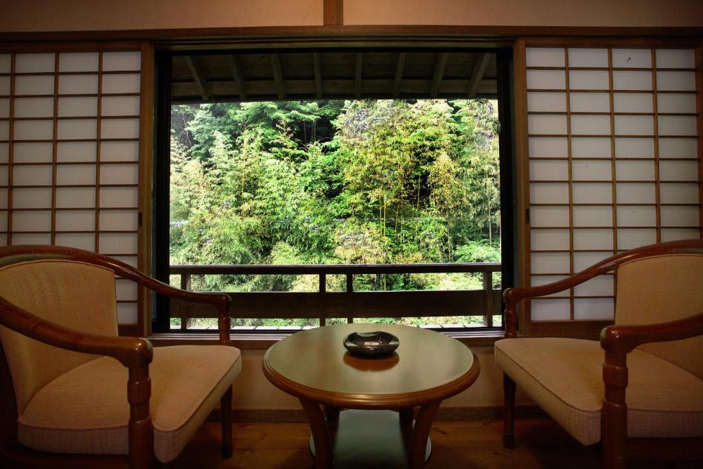 une chambre avec deux chaises, une table et une fenêtre dans l'établissement Yumerindo, à Minamioguni