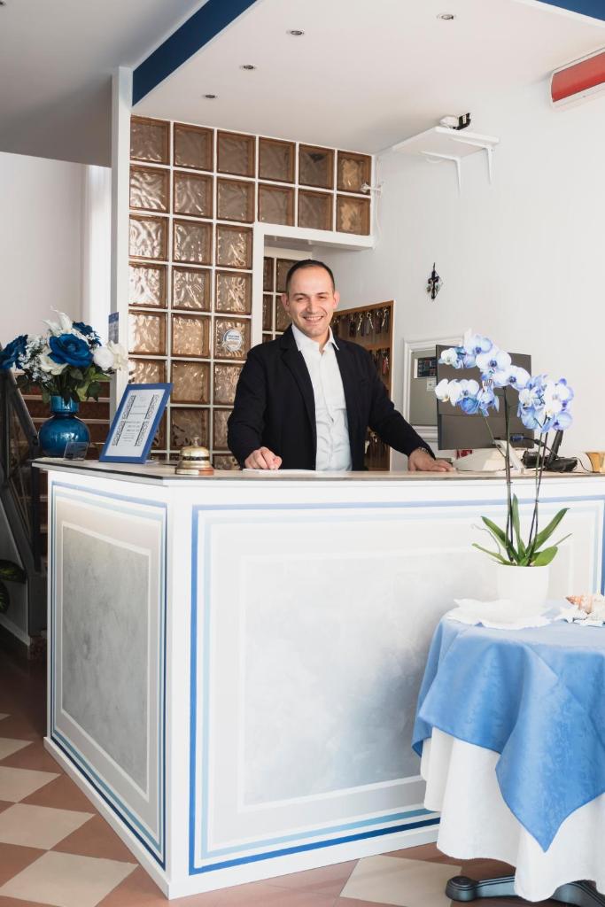 Un homme debout derrière un comptoir dans une pièce dans l'établissement Hotel Cheri, à Rimini 118 autres photos