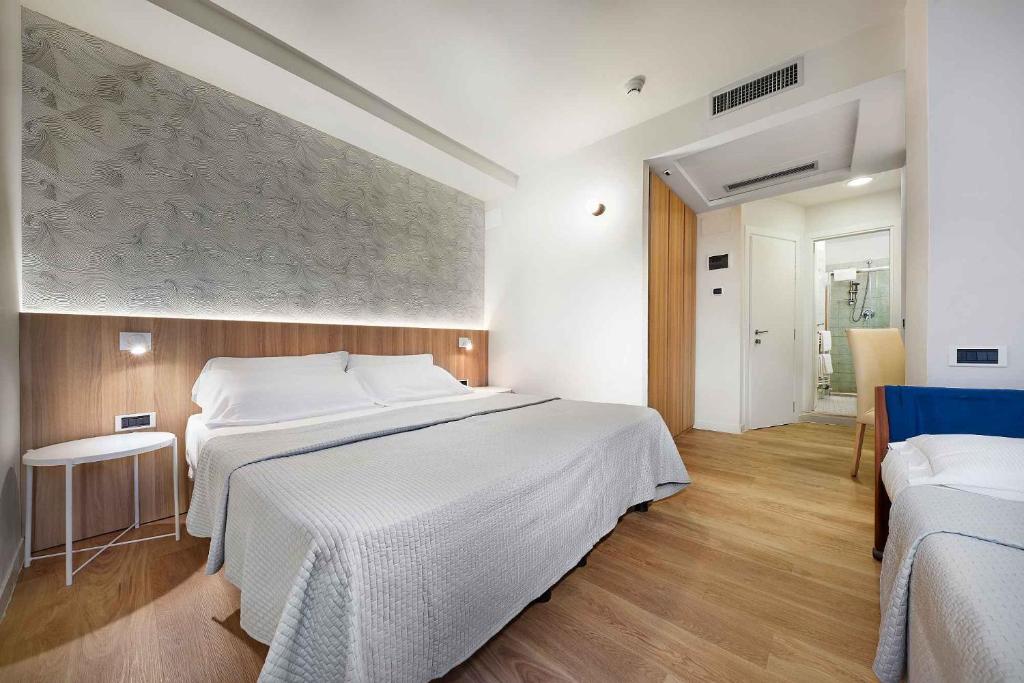 une chambre avec un grand lit blanc dans une pièce dans l'établissement Family Hotel Antibes -50m dal mare -, à Riccione