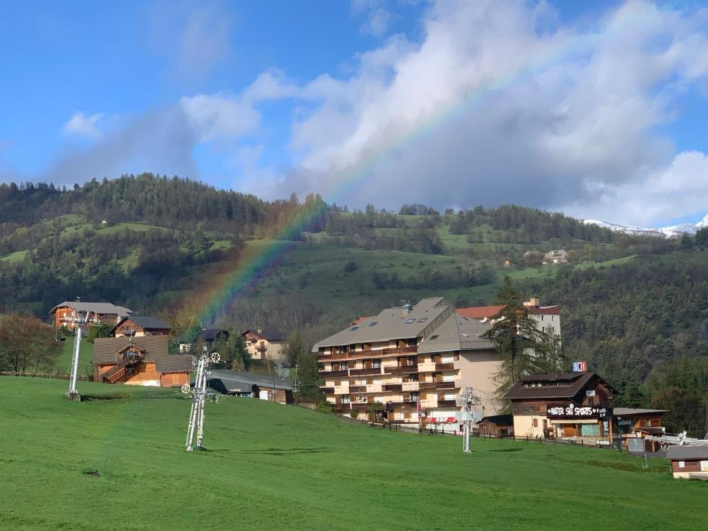 un arc-en-ciel sur un village avec un hôtel et un champ dans l'établissement Hôtel l'Équipe, au Sauze