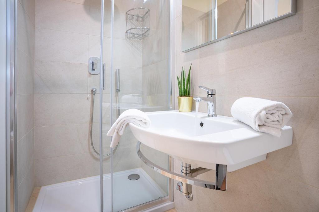 une salle de bain blanche avec lavabo et douche dans l'établissement Hotel Suez, à Lido di Jesolo 59 autres photos