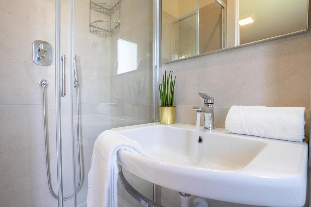 une salle de bain blanche avec lavabo et douche dans l'établissement Hotel Suez, à Lido di Jesolo