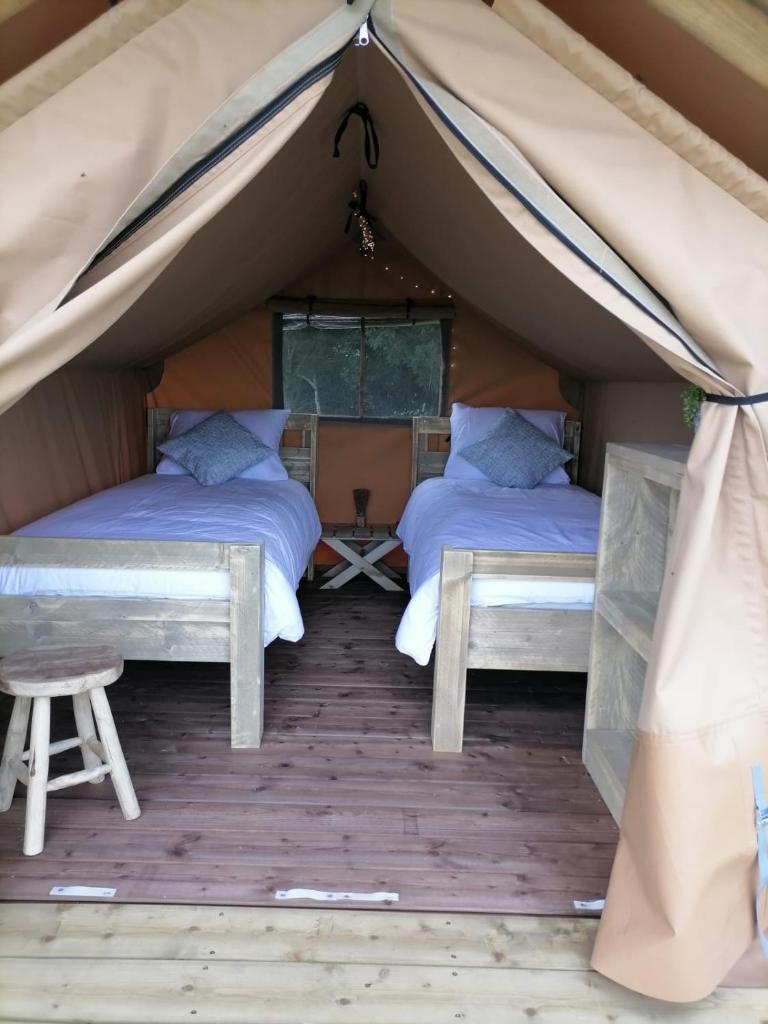 2 lits dans une tente avec une table et un tabouret dans l'établissement FERME DU CAROIRE, à Azay-le-Ferron 14 autres photos