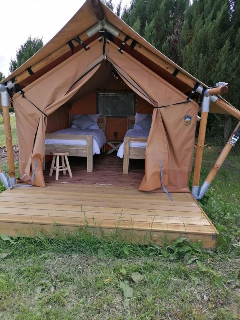 une tente avec 2 lits sur une terrasse en bois dans l'établissement FERME DU CAROIRE, à Azay-le-Ferron