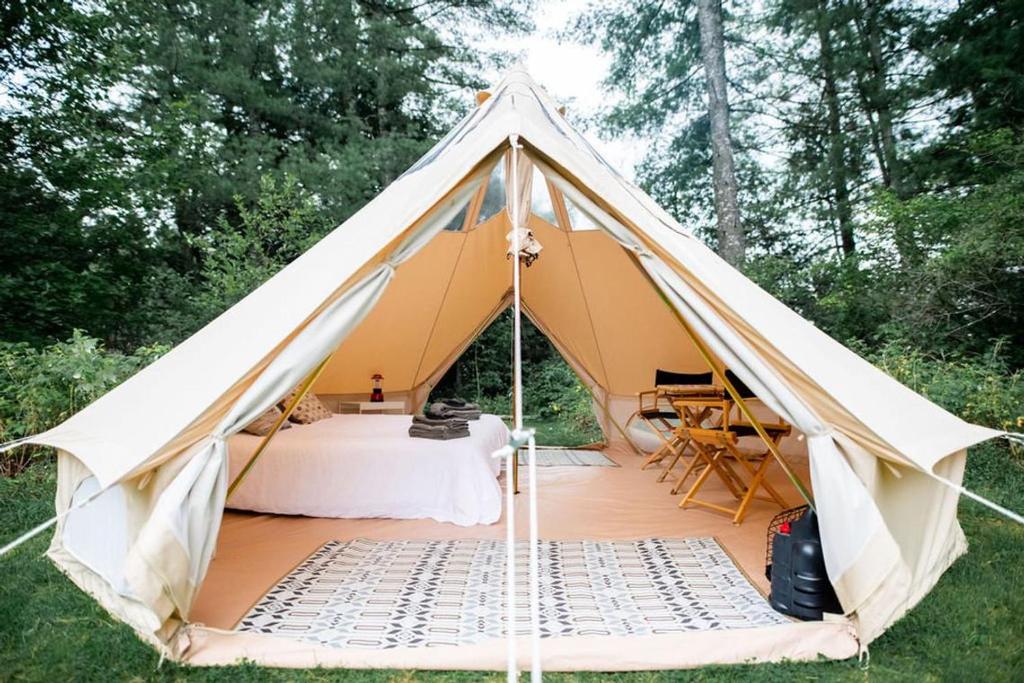 une tente en toile avec un lit et une table dans l'établissement Les Insolites du Domaine d'Haulmé, à Haulmé
