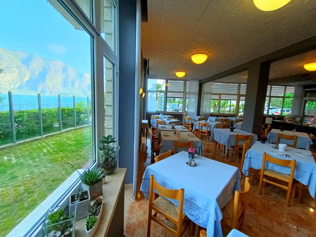 un restaurant avec des tables et des chaises et une grande fenêtre dans l'établissement Hotel Al Molino, à Malcesine