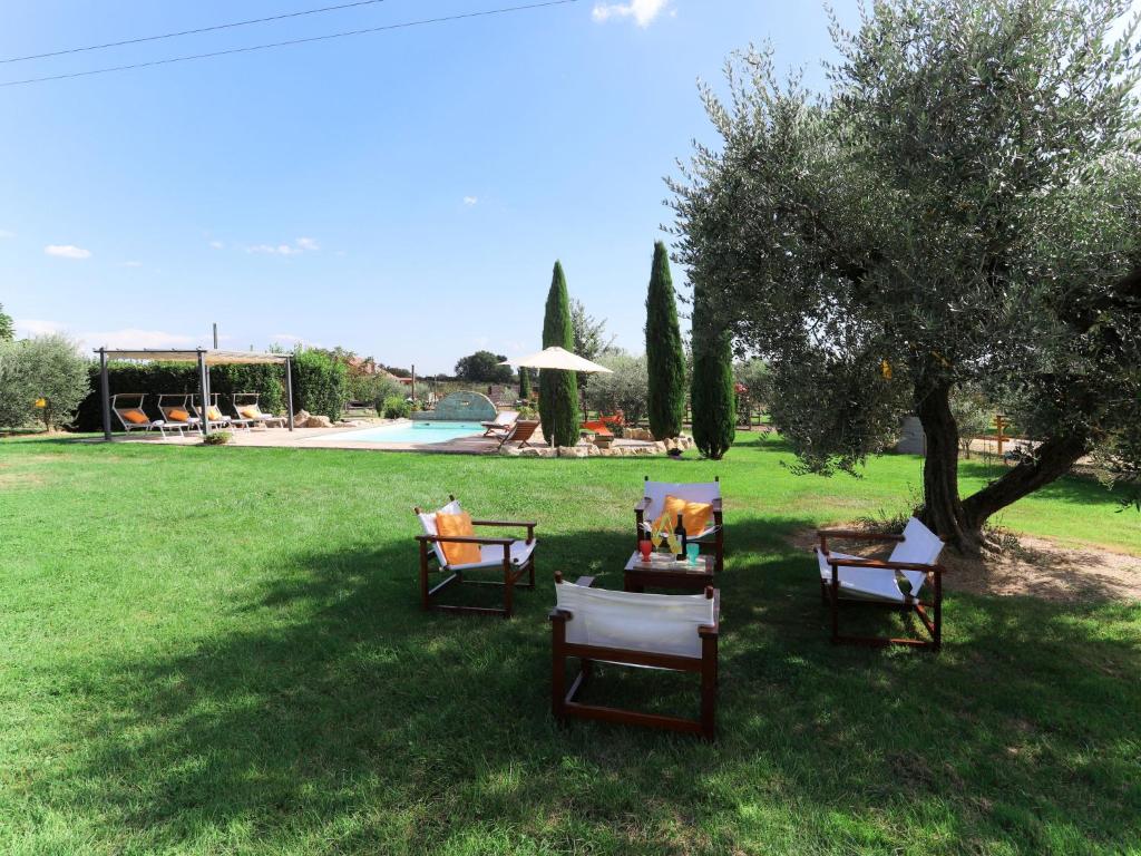 un groupe de chaises assises dans l'herbe près d'un arbre dans l'établissement Villa Cipresso by Interhome, à Sutri