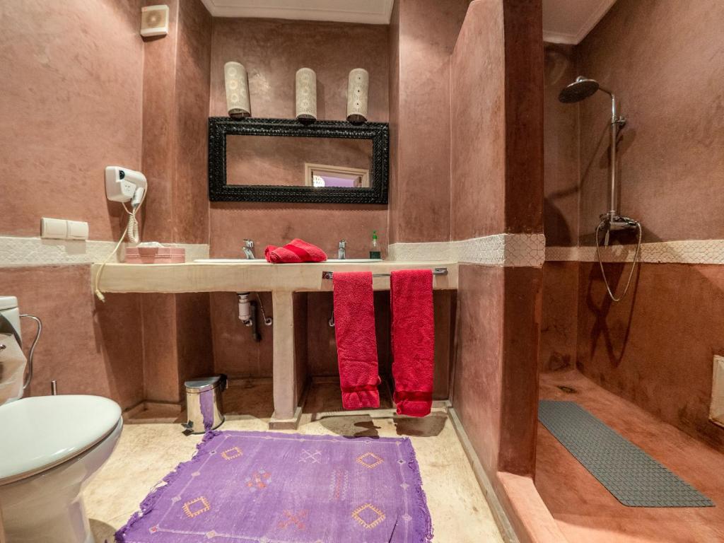La salle de bains est pourvue d'un lavabo, d'une douche et de serviettes rouges. dans l'établissement Riad Tahani, à Marrakech