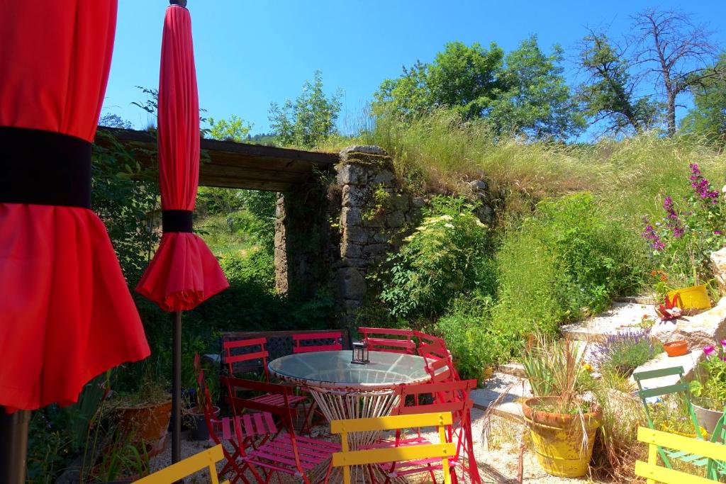 un patio avec une table, des chaises et un parasol dans l'établissement La Ferme De Chenevier, La Roulotte Fleurie 2/4pers, à Saint-Victor