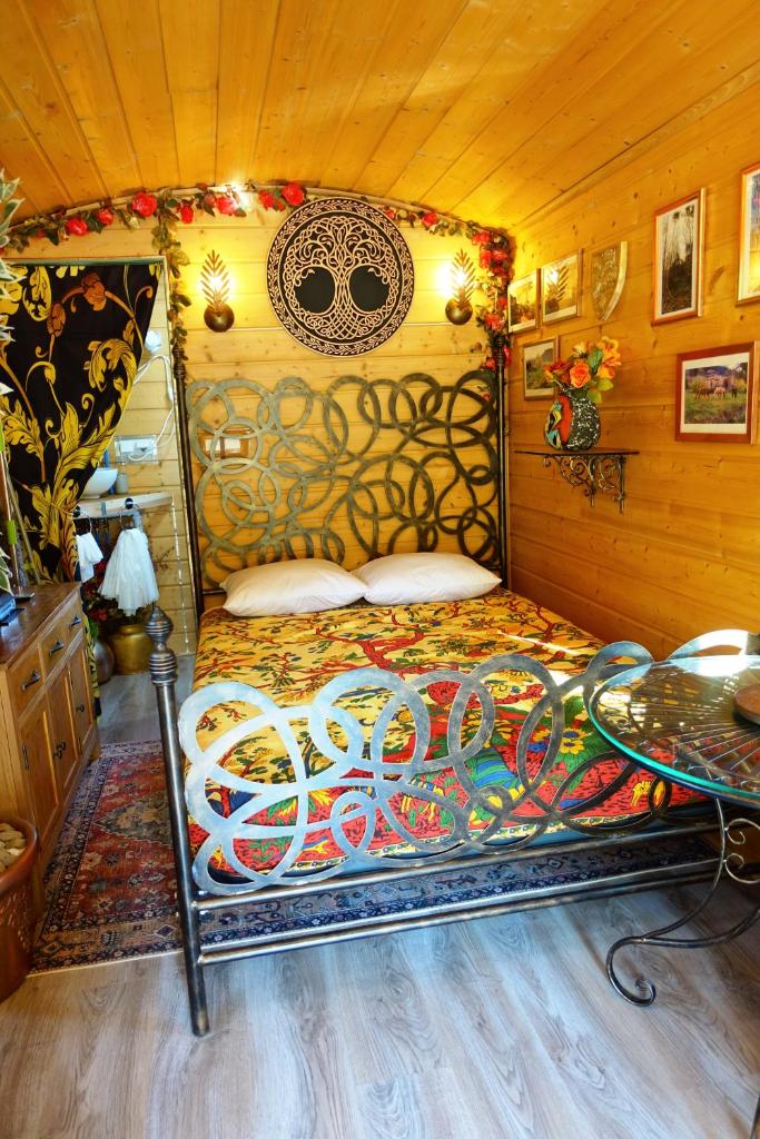 une chambre avec un lit dans une pièce en bois dans l'établissement La Ferme De Chenevier, La Roulotte Fleurie 2/4pers, à Saint-Victor