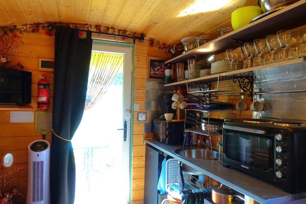 une petite cuisine avec une cuisinière et un micro-ondes dans l'établissement La Ferme De Chenevier, La Roulotte Fleurie 2/4pers, à Saint-Victor 37 autres photos
