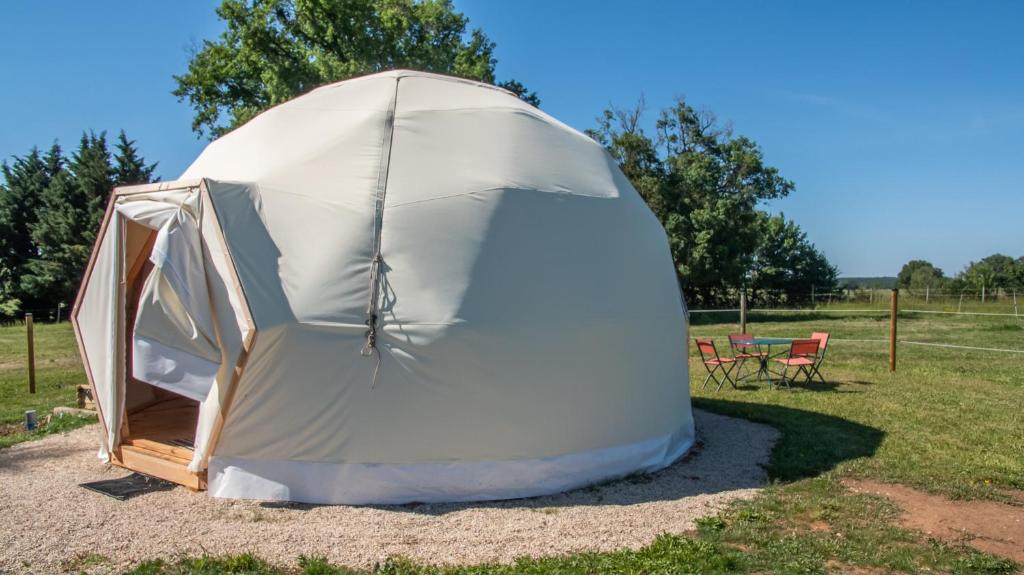 une tente dans un champ avec une table et des chaises dans l'établissement Dome Géodésique, à Gizay 2 autres photos