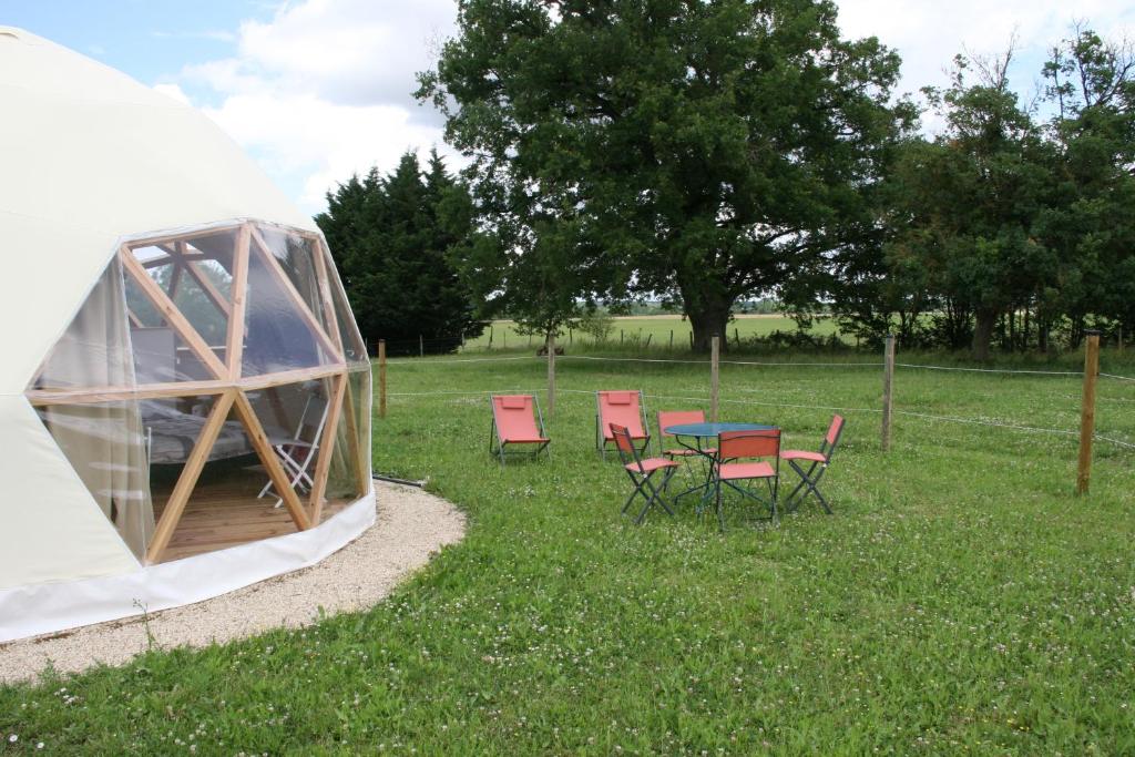 une tente avec des chaises et une table dans l'herbe dans l'établissement Dome Géodésique, à Gizay