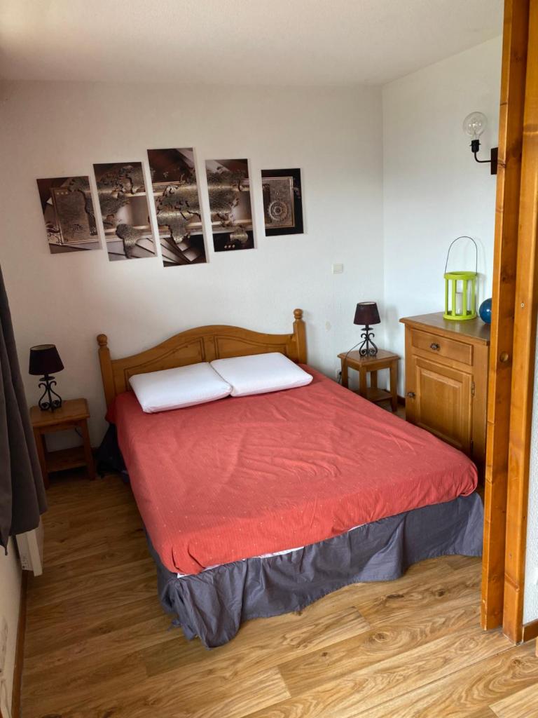 - une chambre dotée d'un lit avec des draps rouges et des photos murales dans l'établissement Skis aux pieds station 1800 Dame Blanche, à Puy-Saint-Vincent