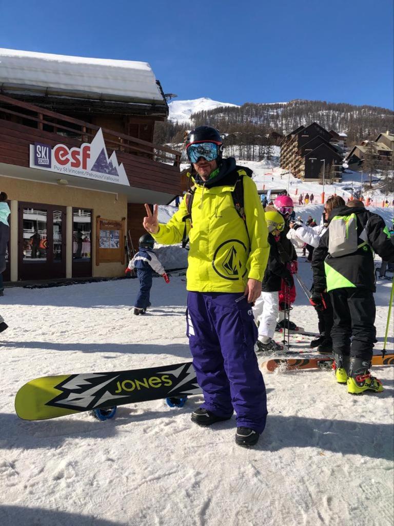 Un homme debout dans la neige à côté d'un snowboard dans l'établissement Skis aux pieds station 1800 Dame Blanche, à Puy-Saint-Vincent
