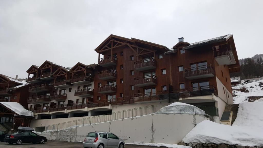 un grand bâtiment avec des voitures garées dans un parking dans l'établissement Skis aux pieds station 1800 Dame Blanche, à Puy-Saint-Vincent