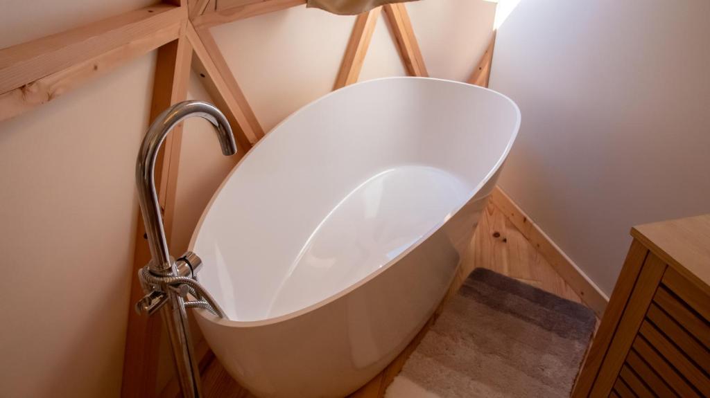 La salle de bains est pourvue d'une baignoire blanche et de parquet. dans l'établissement Dome Géodésique, à Gizay