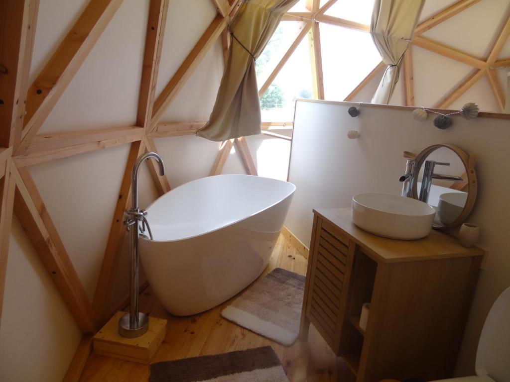 La salle de bains est pourvue d'une grande baignoire et d'un lavabo. dans l'établissement Dome Géodésique, à Gizay