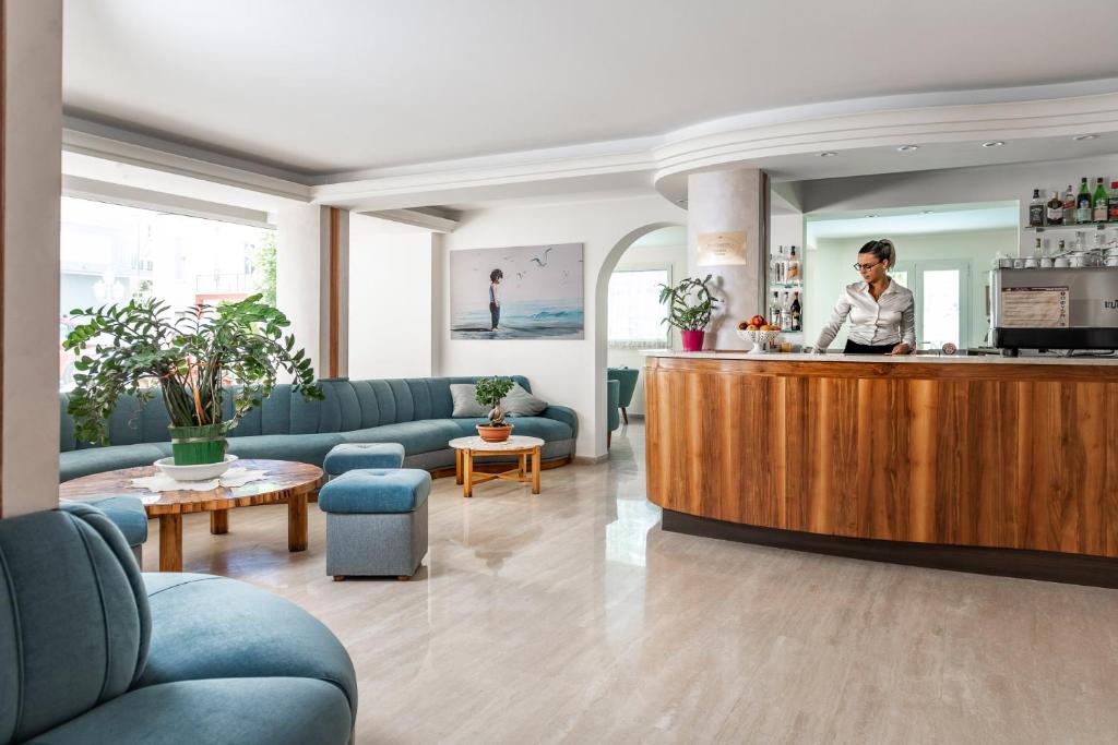 une femme debout à un comptoir dans un hall dans l'établissement Hotel Rondinella e Viola, à Rimini
