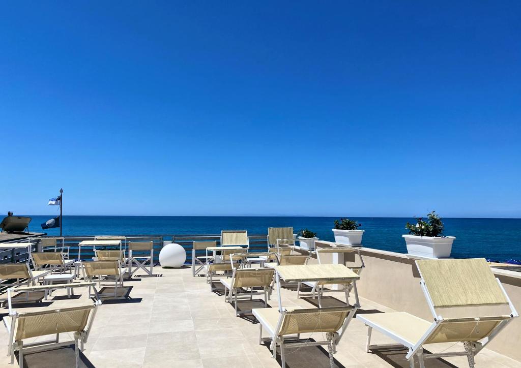 une terrasse avec des chaises et des tables et l'océan dans l'établissement Hotel Cecina Beach, à Marina di Cecina 68 autres photos
