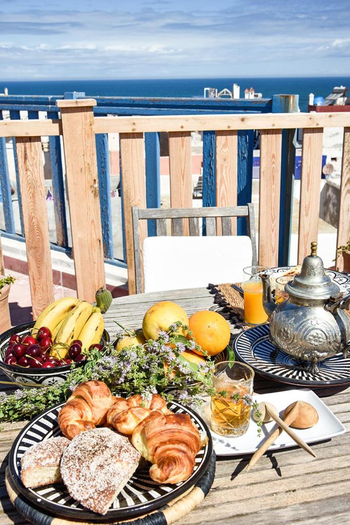 - une table avec des assiettes de nourriture sur une table avec la plage dans l'établissement Riad Lyon-Mogador, à Essaouira