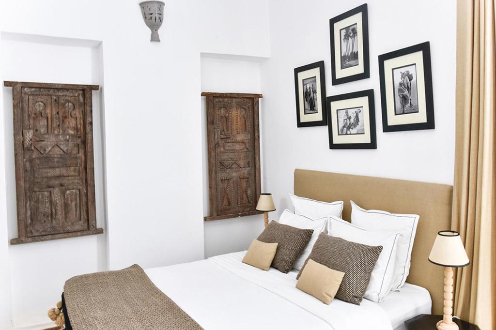 - une chambre avec un lit blanc et quelques photos sur le mur dans l'établissement Riad Lyon-Mogador, à Essaouira