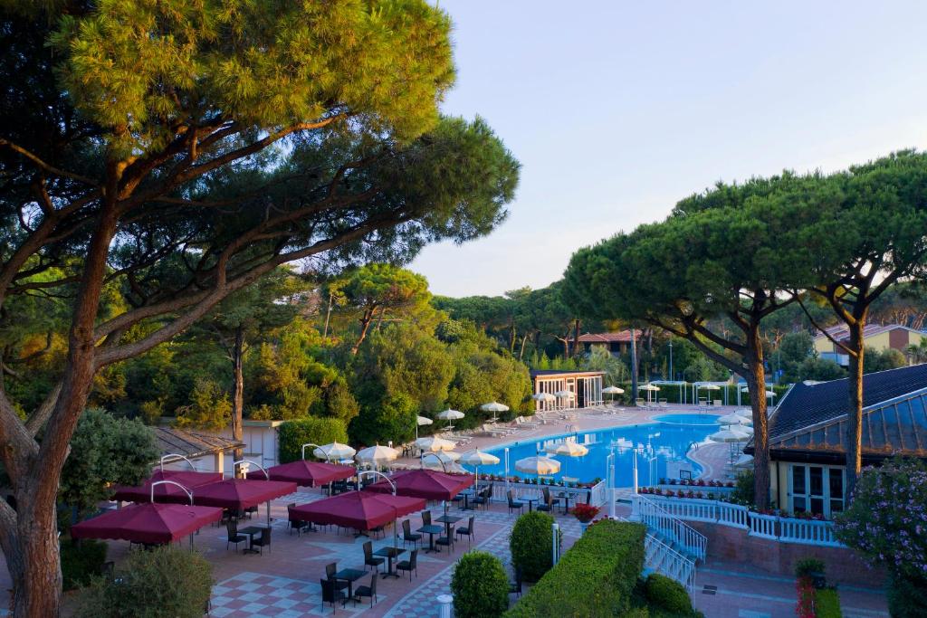 - une vue sur la piscine d'un complexe avec des parasols rouges dans l'établissement Park Hotel Marinetta - Beach & Spa, à Marina di Bibbona