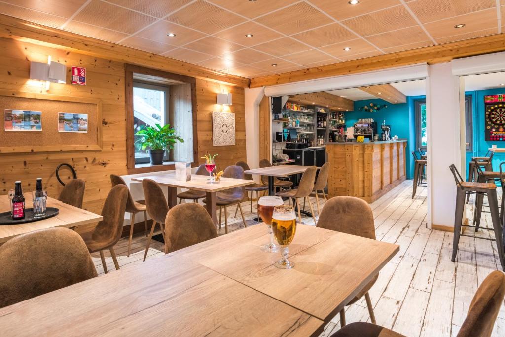 un restaurant avec des murs en bois, des tables et des chaises dans l'établissement Hôtel Les Essarts, USSIM Vacances, à Valloire