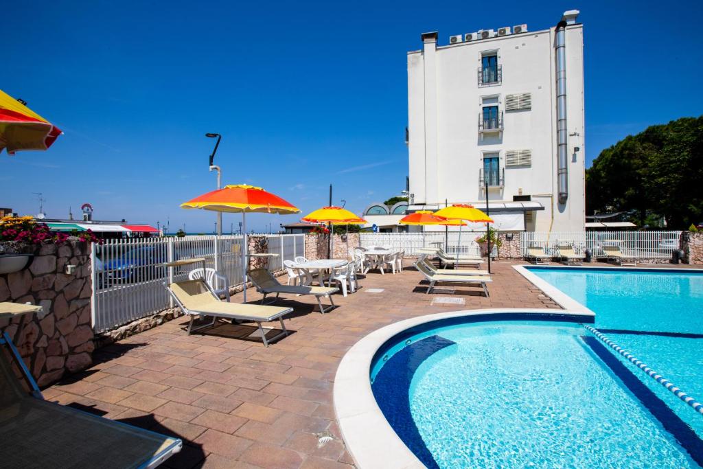 une piscine avec chaises et parasols à côté d'un bâtiment dans l'établissement Miramare Hotel Ristorante Convegni, à Cesenatico