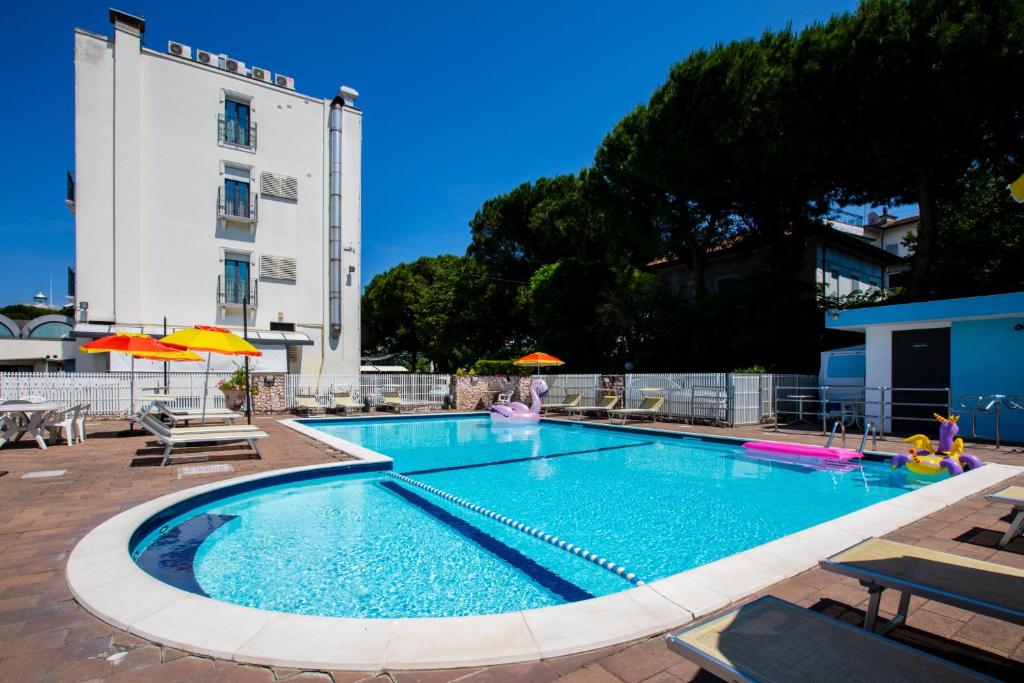 une piscine avec chaises et parasols à côté d'un bâtiment dans l'établissement Miramare Hotel Ristorante Convegni, à Cesenatico
