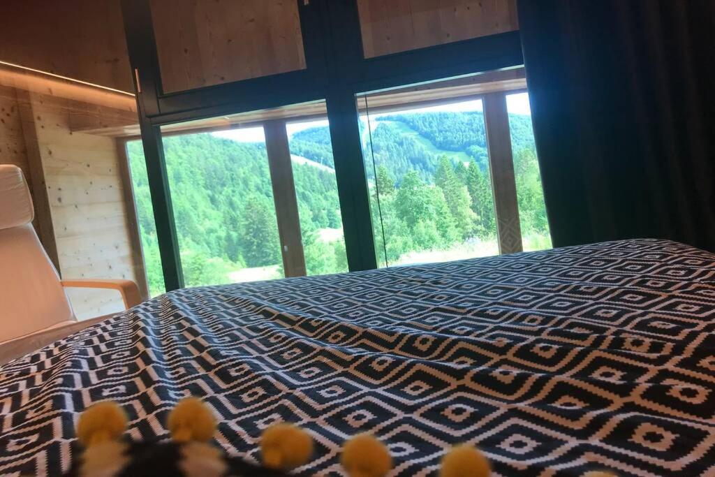 une chambre avec un lit et une grande fenêtre dans l'établissement Bel appartement neuf équipé au pied des pistes du HONHECK, à La Bresse