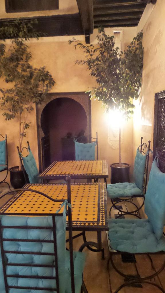 - deux tables et des chaises dans une pièce avec cheminée dans l'établissement Riad Sabbah, à Marrakech
