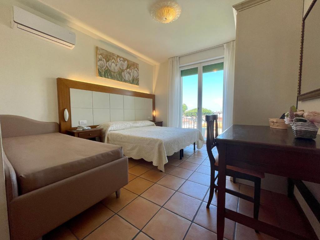 une chambre d'hôtel avec un lit, un bureau et un canapé dans l'établissement Hotel Sylvia, à Lido di Camaiore