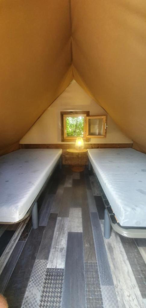 deux lits dans une petite pièce avec une fenêtre dans l'établissement Les lodges du Moulin, à Saint-Laurent