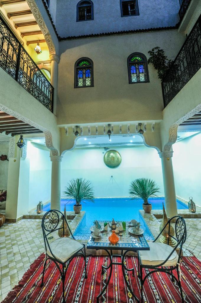 une chambre avec une table, des chaises et une piscine dans l'établissement Riad Milouda, à Marrakech