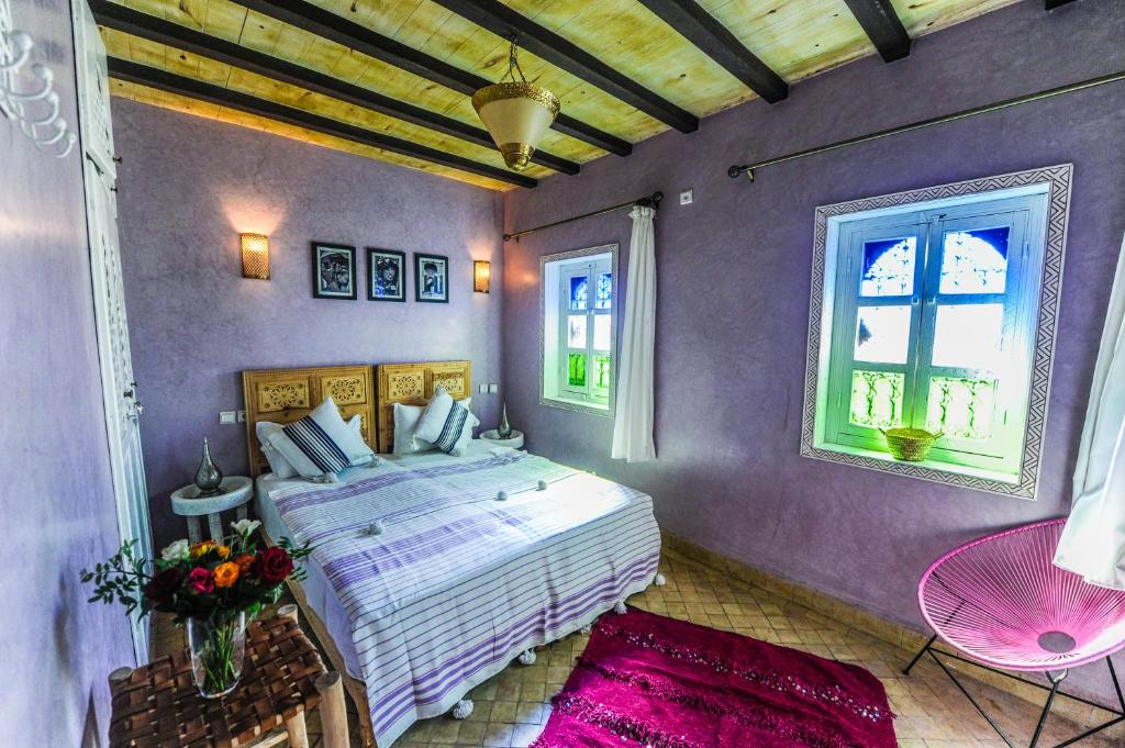 - une chambre avec un lit et un mur violet dans l'établissement Riad Milouda, à Marrakech
