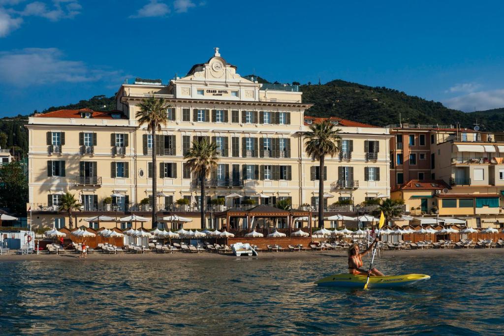 une personne dans un kayak dans l'eau devant un bâtiment dans l'établissement Grand Hotel Alassio Beach & Spa Resort - The Leading Hotels of the World, à Alassio