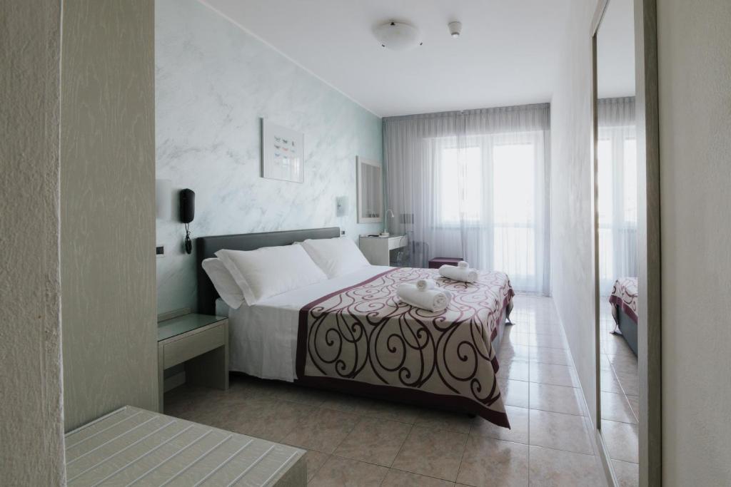 une chambre avec un lit avec une table et une fenêtre dans l'établissement Hotel Gloria, à Lignano Sabbiadoro
