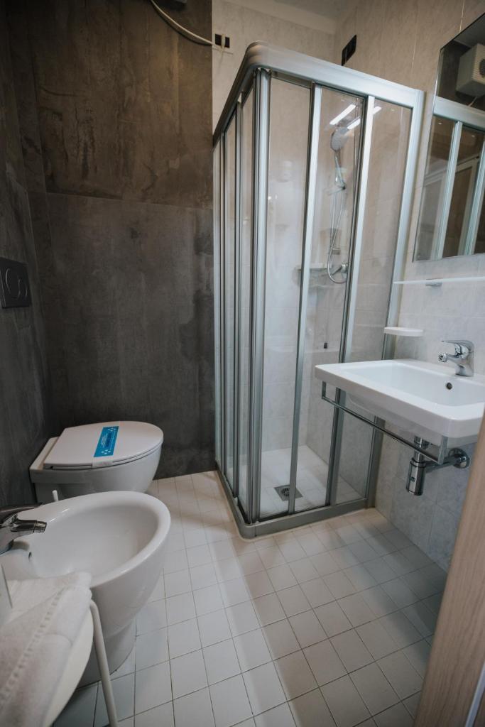 une salle de bain avec une douche, des toilettes et un lavabo dans l'établissement Hotel Gloria, à Lignano Sabbiadoro