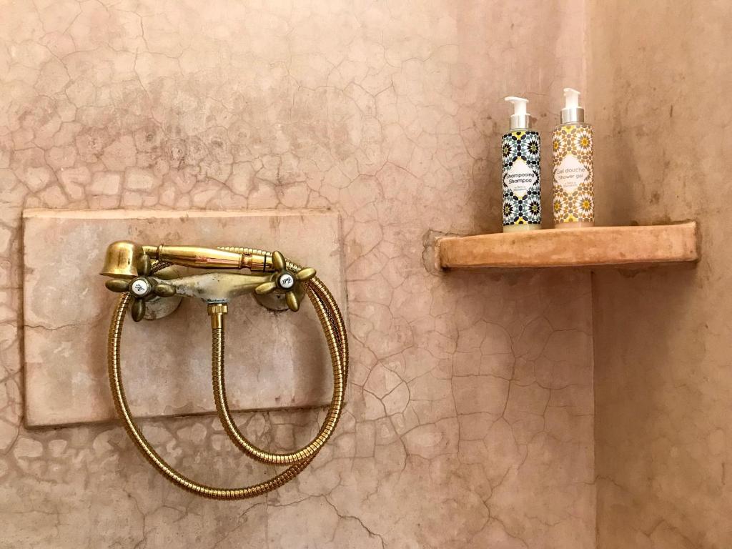 La salle de bains est pourvue d'une douche avec un tuyau et 2 bouteilles. dans l'établissement Riad Dar Zaman, à Marrakech