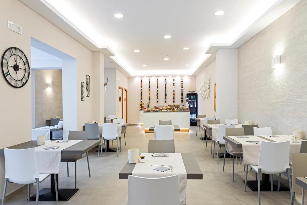 un restaurant avec des tables et des chaises blanches et une horloge dans l'établissement Hotel Biagi & Residence, à Lido di Camaiore