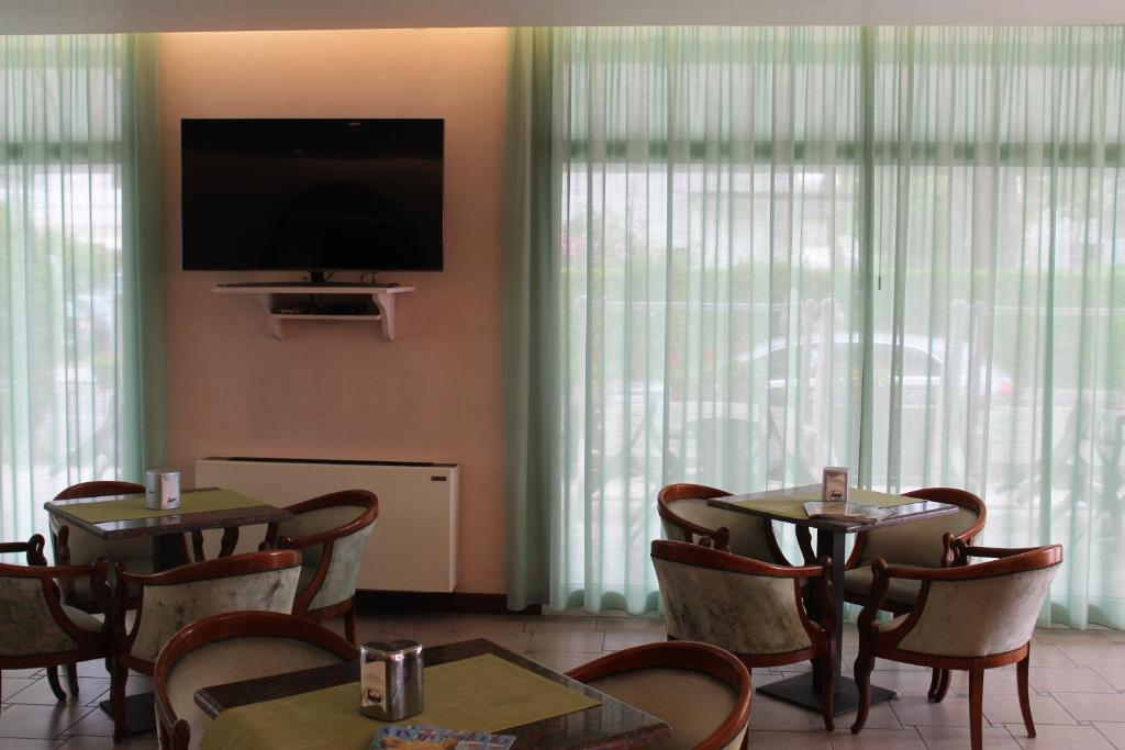 une salle à manger avec tables et chaises et une télévision à écran plat dans l'établissement Hotel Palme Park & Beach included, à Lido di Jesolo