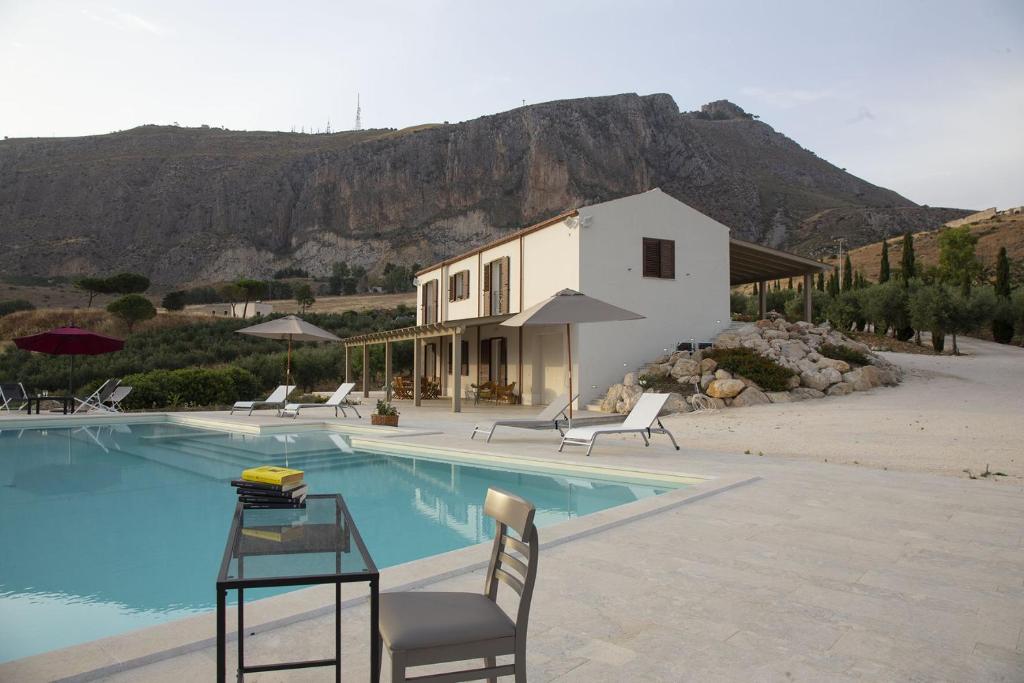 une piscine avec des chaises et une maison avec une montagne dans l'établissement Tenuta Torrebianca Villa con Piscina panoramica, à Erice