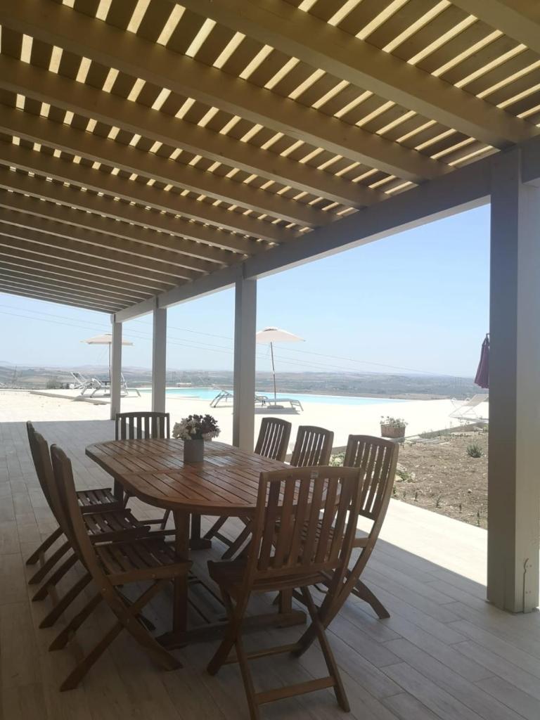 - une table et des chaises en bois sur une terrasse donnant sur la plage dans l'établissement Tenuta Torrebianca Villa con Piscina panoramica, à Erice