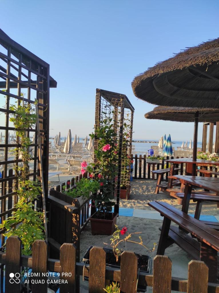 un patio avec des bancs, des tables et des fleurs dans l'établissement Hotel Imperiale, à Cesenatico