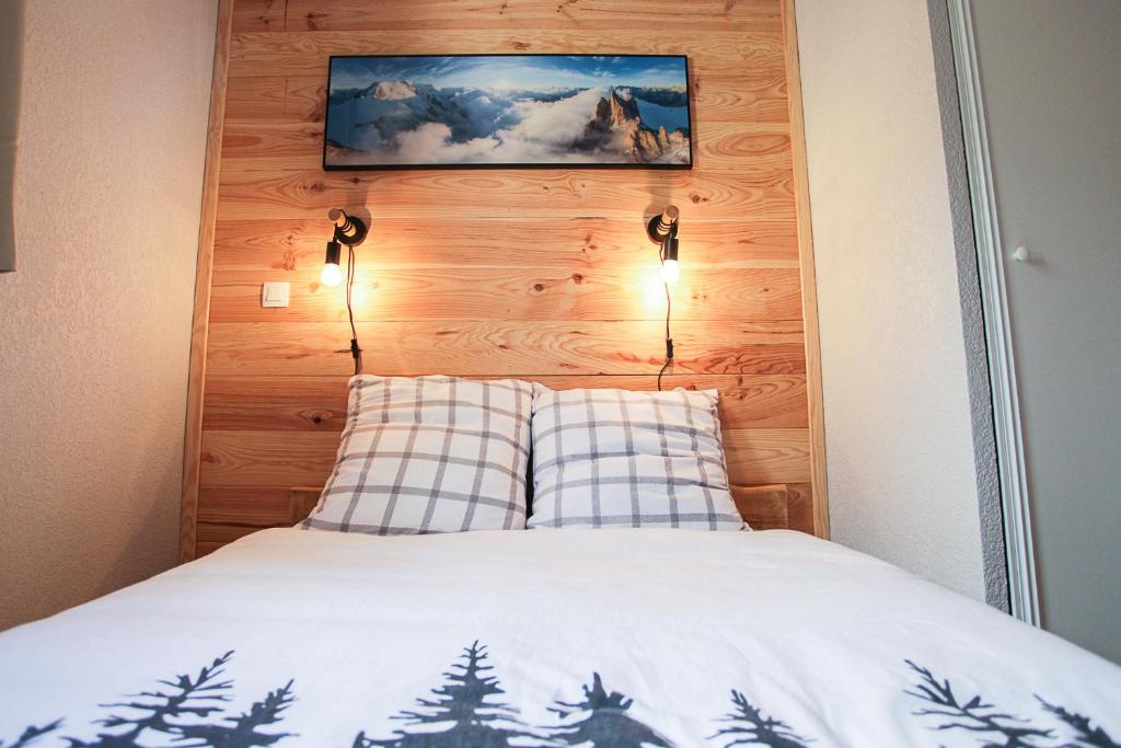 - un lit avec une tête de lit en bois et une photo au-dessus dans l'établissement L'Alpin- Appartement 2ch au pied des pistes- tarif lits faits et linge de toilette compris, à Aussois