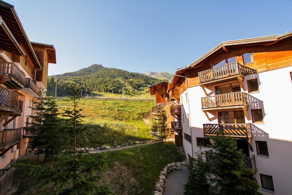 Une allée entre deux bâtiments avec des montagnes en arrière-plan dans l'établissement L'Alpin- Appartement 2ch au pied des pistes- tarif lits faits et linge de toilette compris, à Aussois