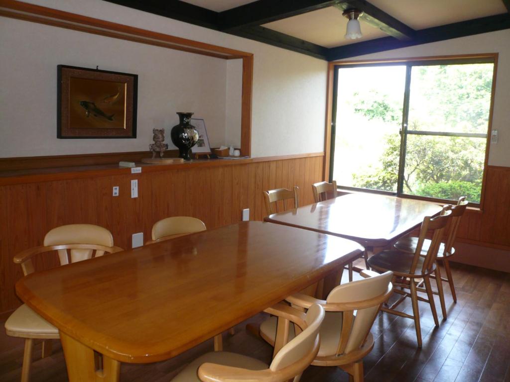 une salle à manger avec une grande table et des chaises en bois dans l'établissement Yufuin Onsen Hasuwa Inn, à Yufu
