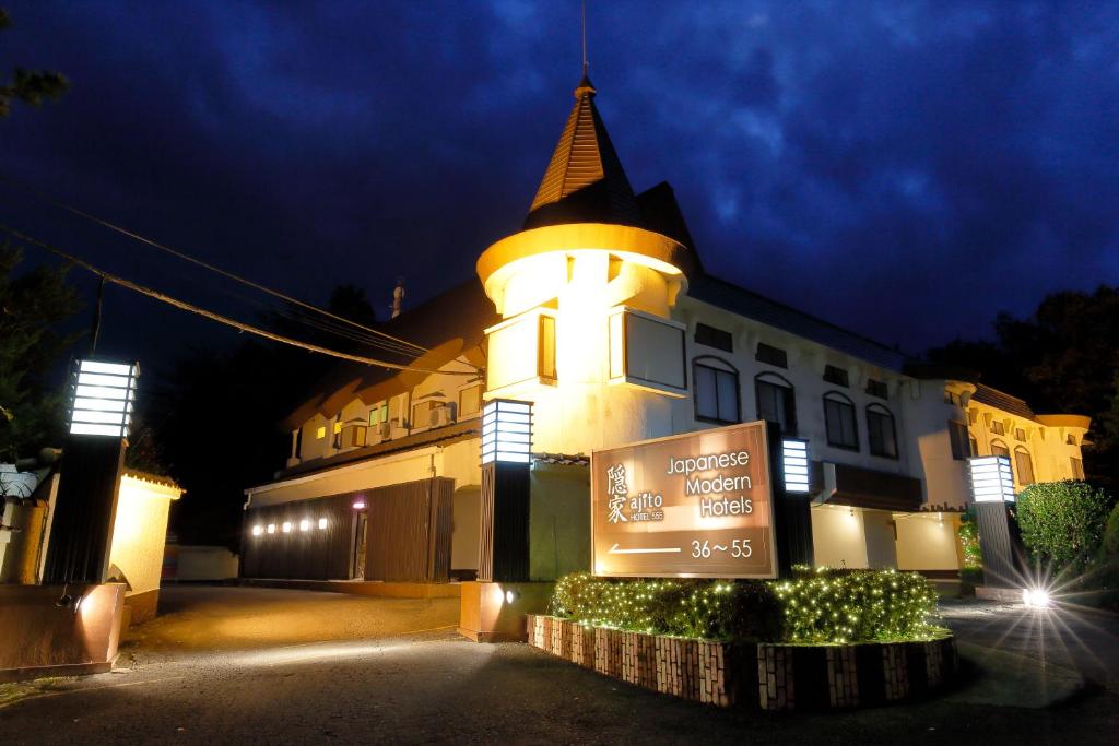 un bâtiment avec une tour et un panneau en face de celle-ci dans l'établissement 隠家(ajito) HOTEL555 御殿場2, à Gotemba